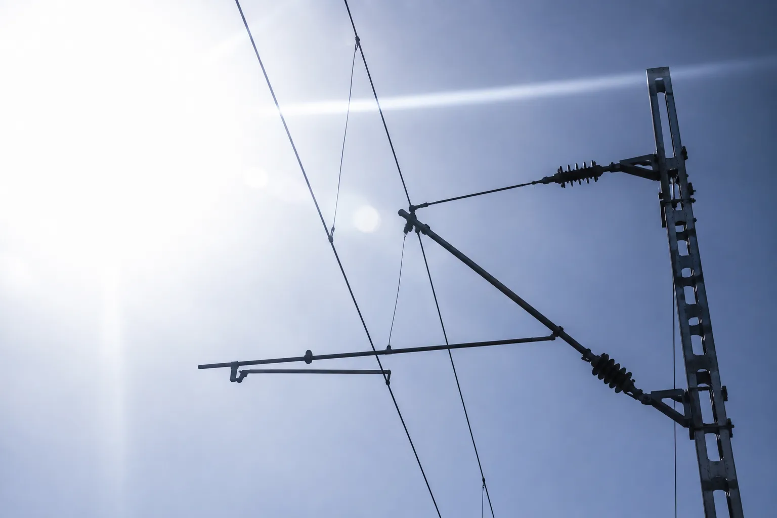 Contact wire & mast silhouetted against harsh backlight & glare, a tough view for vehicle mounted computer vision